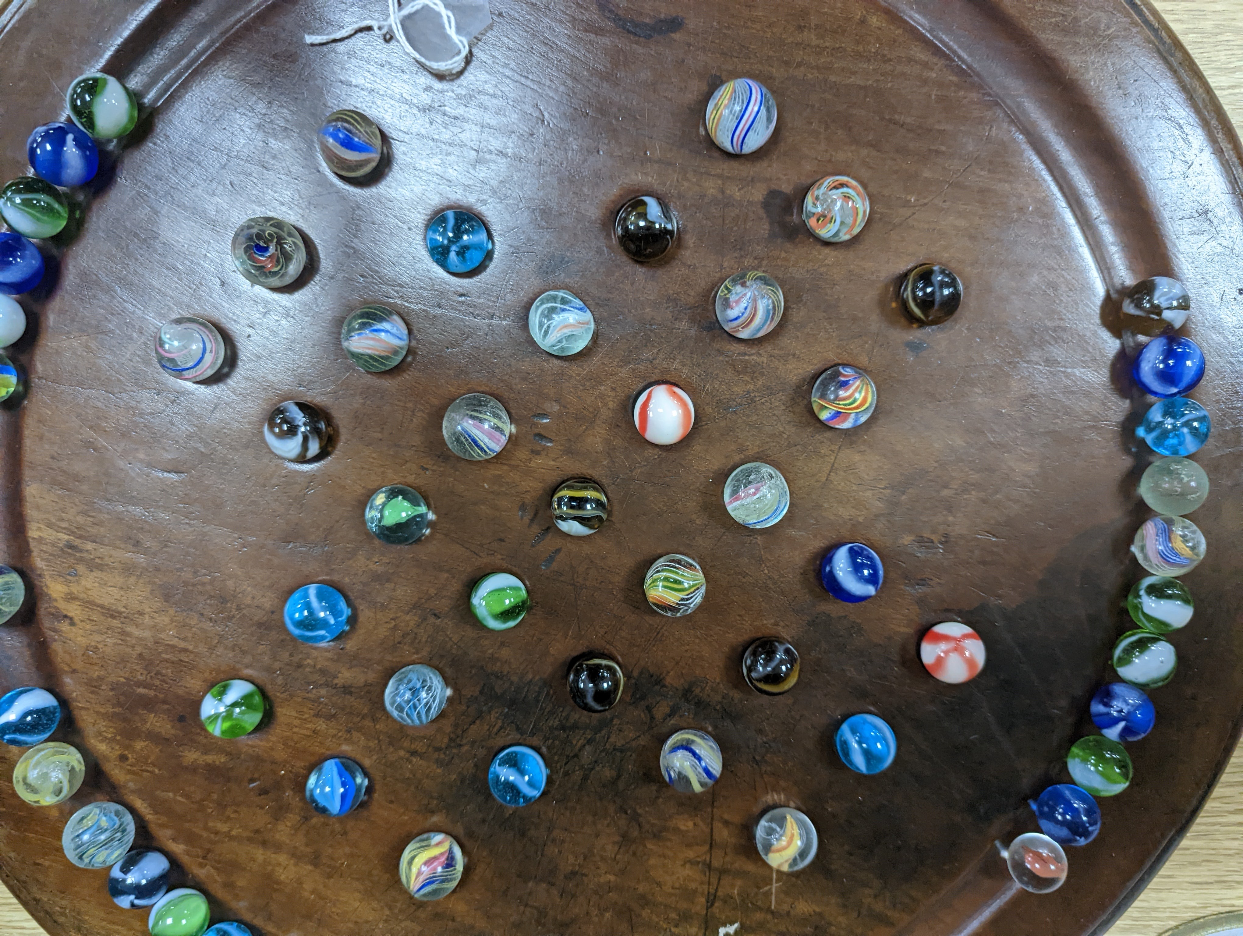 A collection of glass marbles and a mahogany solitaire board 45cm